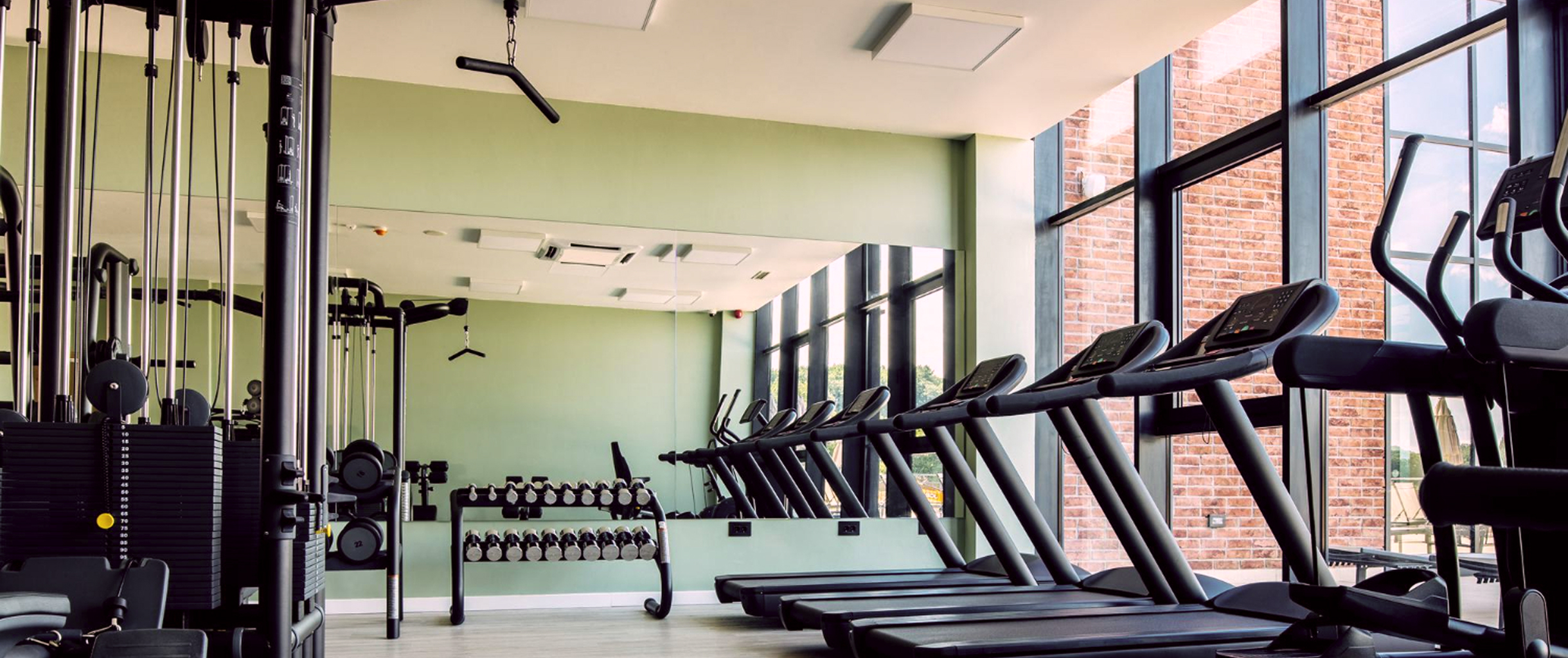 На картинке изображен тренажерный зал с беговыми дорожками, гантелями, тренажёрами, зеркалами